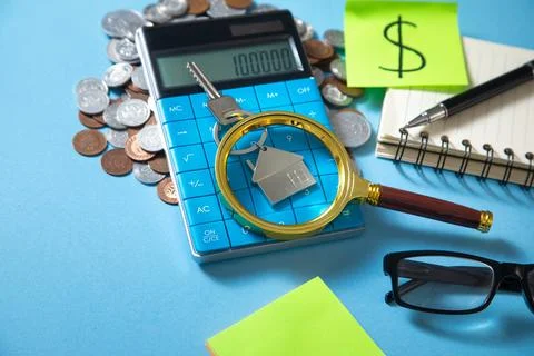 House keys, calculator and stack of coins. Stock Photos