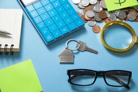 House keys, calculator and stack of coins. Stock Photos