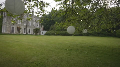 A house with a large yard and a tree with white balloons hanging from it Video stock 301794819