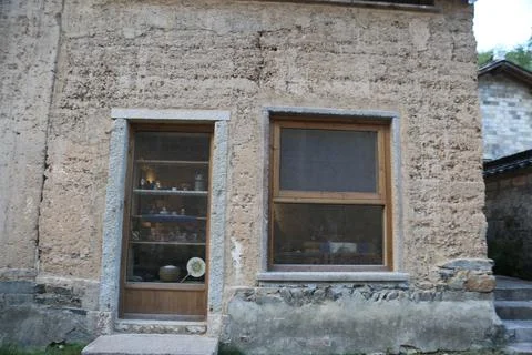 The house is made of adobe, with an open window and a glass cabinet on the .. Stock Photos