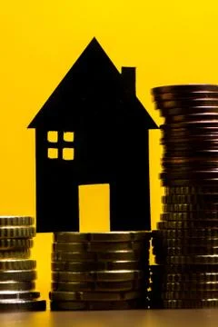 A house made of blackboard and a stack of euro coins in a yellow background Stock Photos