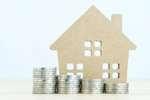 House model and stack of coins on table Stock Photos