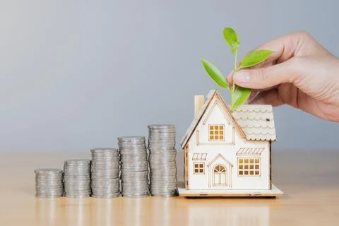 House model with money coins stack and green plant on hand holding. Stock Photos