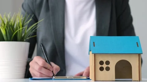 House model on the table, blurred female hands signing mortgage loan agreement Stock Footage 250628521