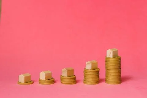 House Models On Top Of Increasing Stacked Coins Over Pink Background. Mortgage Stock Photos