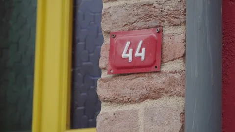House number 44 on brick wall next to yellow door and red painted exterior .. Vídeos de archivo 332108677