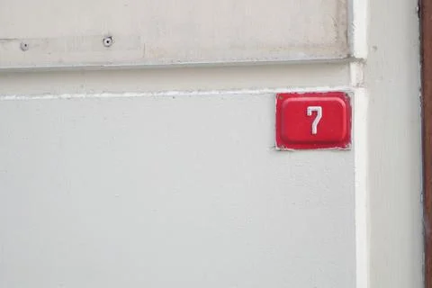 House number 7 is shown on a plain wall in a city Stock Photos