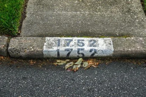 House numbers painted on a street curb at he end of a concrete sidewalk Stock Photos