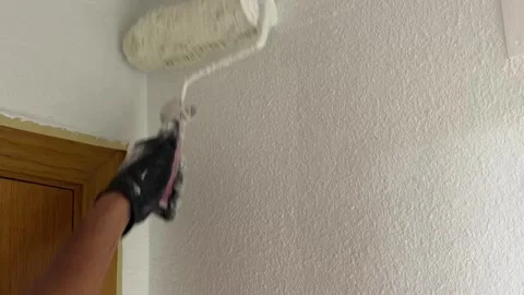 House painter applying fresh white paint on a textured wall Stock Footage 341362978