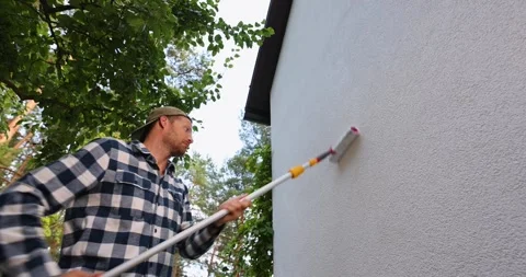 House painter applying protective coating on house exterior wall with rolle.. Stock Footage 341576434