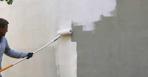 House painter painting building exterior with roller Stock Footage