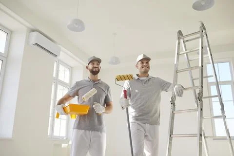 House painters standing in empty room near ladder preparing for painting the Fotos Stock