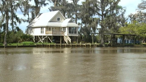 House with pier near river with motor boat riding on water, New Orleans, US Stock Footage 132394853