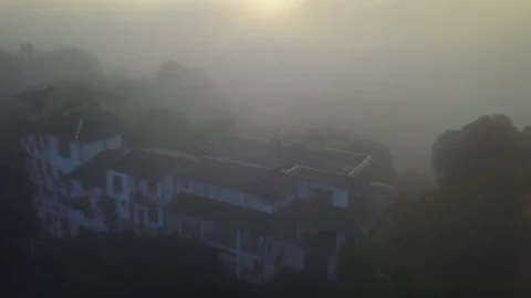 House in the rays of the sun through the fog in hills in Kandy drone footage Stock Footage 85079006