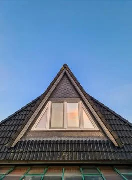 House roof gable with triangular window against blue sky 写真素材