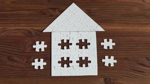 House-Shaped Puzzle with Missing Pieces on Wooden Table Stock Footage 295114477