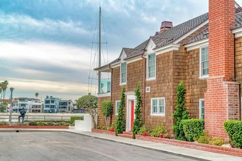House with shingle cladding on exterior wall against sky with gray clouds Stock Photos