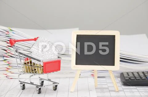 House in shopping cart with gold coins and empty blackboard Stock Photos
