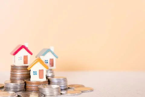 House on stack coins isolated orange background. Saving money and investment  Stock Photos