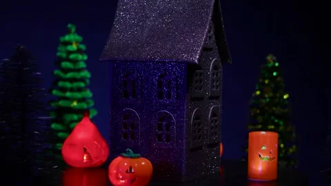 A house surrounded by glowing pumpkins rotates against a dark blue background Stock Footage 319262860