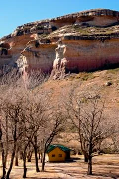 House surrounded by leafless trees below multi-tiered mountain Stock-Fotos