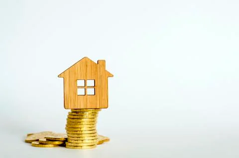 The house symbol is made of bamboo on a stack of yellow shiny coins on a ligh Foto stock