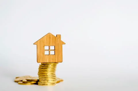 The house symbol is made of bamboo on a stack of yellow shiny coins on a ligh Stock Photos
