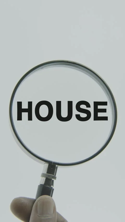 House text or word highlighted by a magnifying glass in a hand on a white Stock Footage 303452876