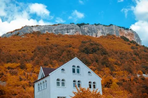 House under a large rock and autumn nature. Stock Photos