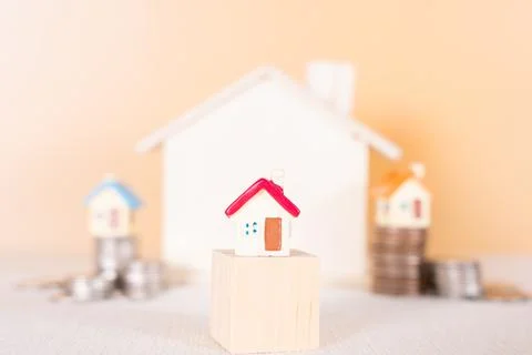 House on wooden block and stack coins isolated orange background. Saving mone Stock Photos