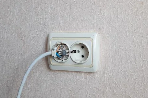 Household electrical outlet with a broken electrical plug inside. Bare live Stock Photos