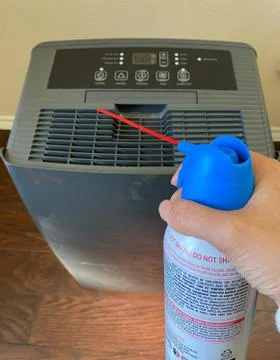 Household using the air duster to clean the air vent of dehumidifier Stock Photos