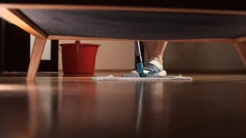 Housekeeper cleaning floor under couch with mop Stock Footage 306148659