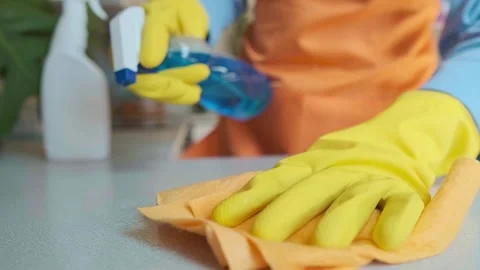 Housekeeper in uniform sprays cleaning solution on the table surface and wipes i Stock Footage 301868119