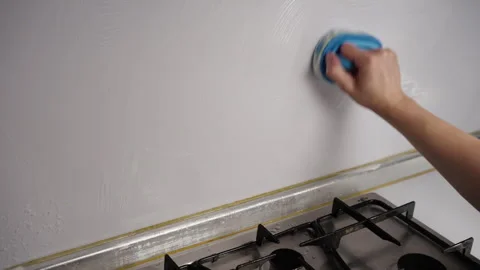 Housekeeper using cleaning brush and detergent to scrub white textured wall in Stock Footage 305999748