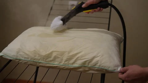 Housekeeper using a steam cleaner to clean pillow, removing dust mites, bed bugs Stock Footage 295815181