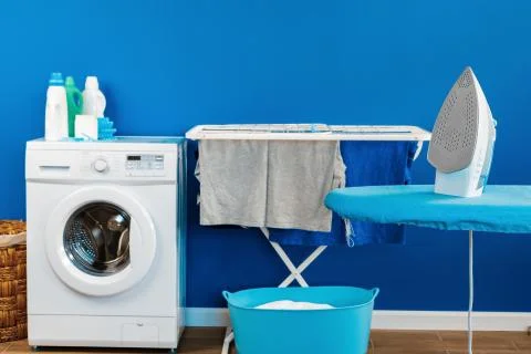 Housekeeping concept. Washing machine and ironing board Stock Photos