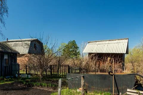 Houses and trees on a garden plot against the background of the sky. Stock Photos