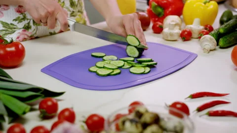 Housewife cuts cucumber with sharp knife on chopping board Stock Footage 229723940