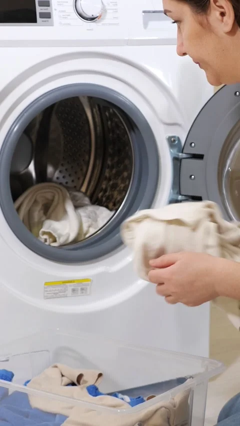Housewife loading clothes into washing machine for doing laundry, woman putting Stock Footage 341677222