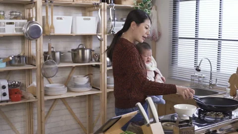 Housewife preparing breakfast while rocking child Video stock 137376669