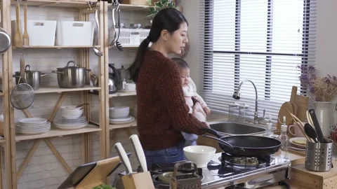 Housewife preparing breakfast while rocking child Stock Footage 139188016