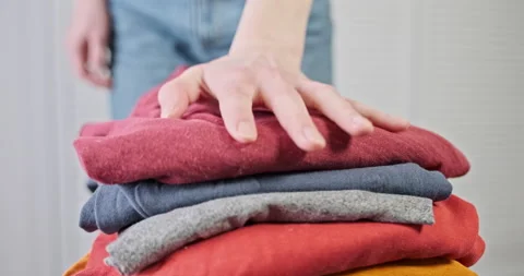 Housewife presses stack of clean clothes with her hand, close-up. Stock Footage 236305527