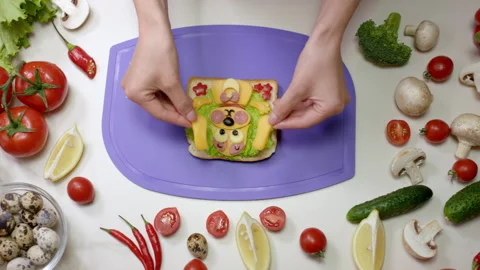 Housewife puts tiny pieces of cheese on vegetable sandwich Stock Footage 237003993