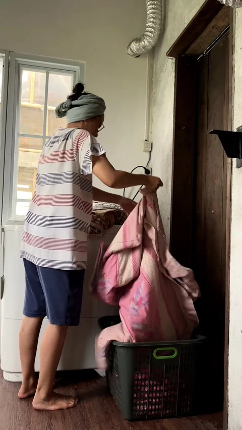 A Housewife Is Sorting Blankets To Be Washed Into A Laundry Basket Vídeo Stock 345043827