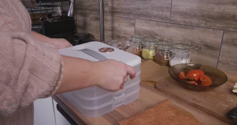 Housewifes hands opening a multi-layered plastic food container on a kitchen Stock Footage 329860167