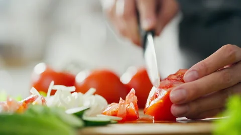 Housewifes hands using a knife to slice juicy tomatoes on cutting board whil 動画素材 246750584
