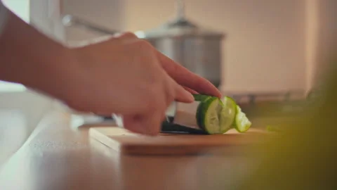 A housewifes skilled hands carefully slice a fresh green cucumber on a kitch Stock Footage 346388068