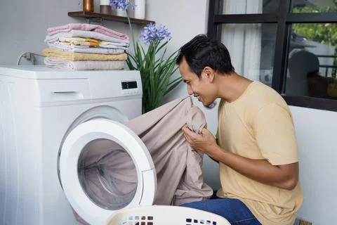 Housework. asian Man loading clothes into washing machine Stock-Fotos