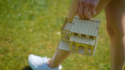 Housing relocation concept with miniature house carried in hands. Woman walking Stock-Footage 336107671